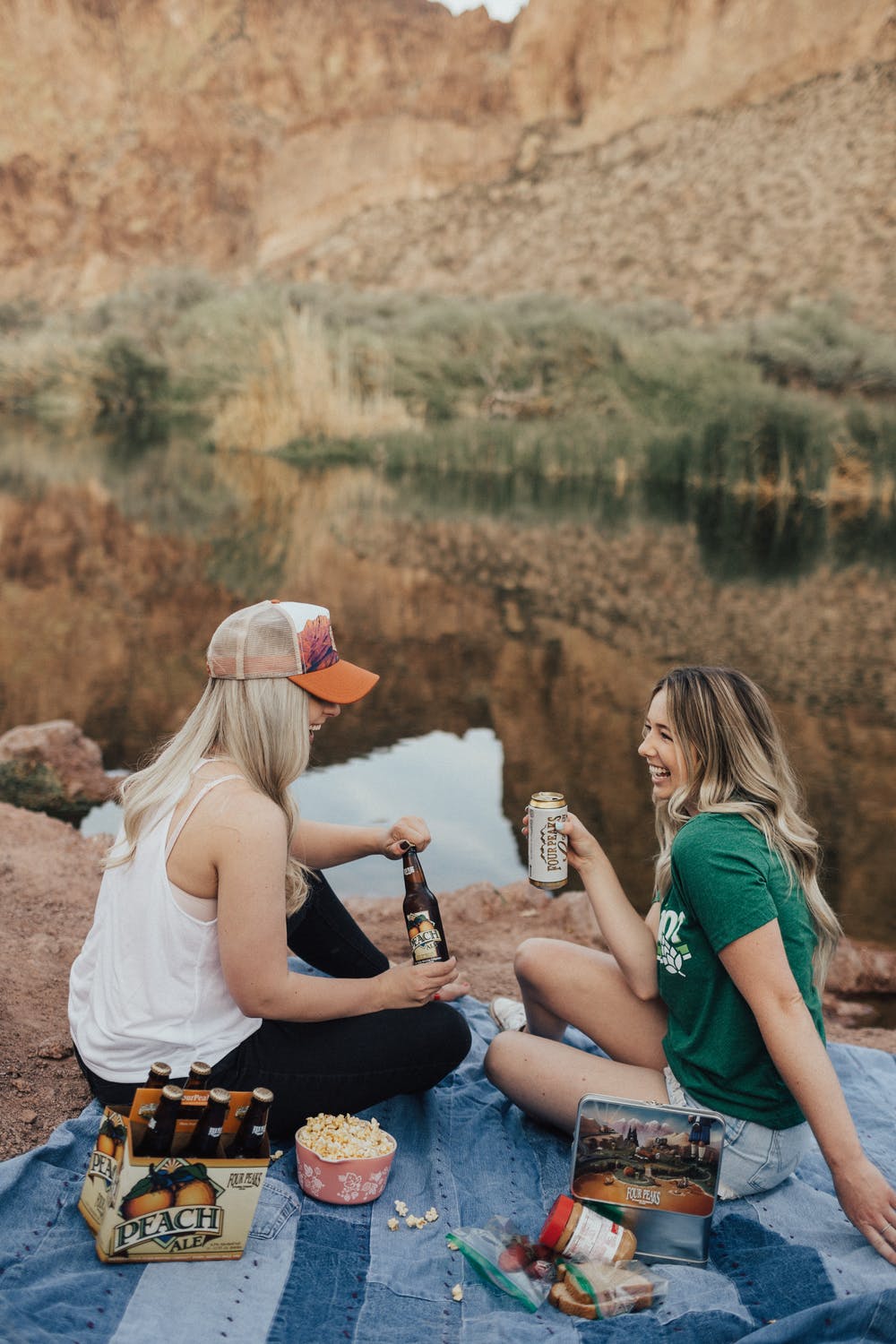 a group of women sitting on a rock with a bottle of wine