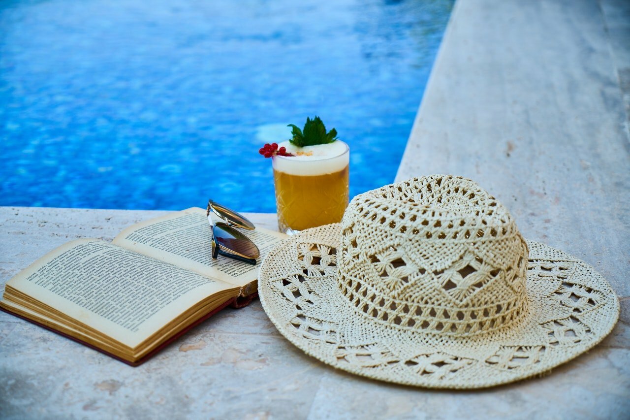 a pair of glasses with a drink and a straw on a towel by a pool