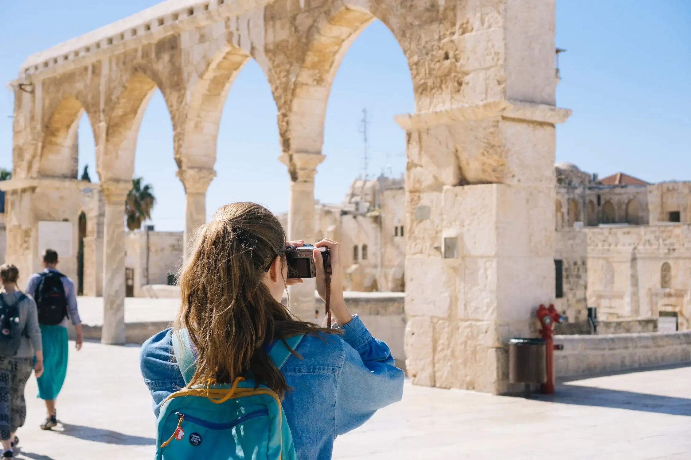 Traveler photographing ancient stone archway, inspiring vacation ideas and destinations.